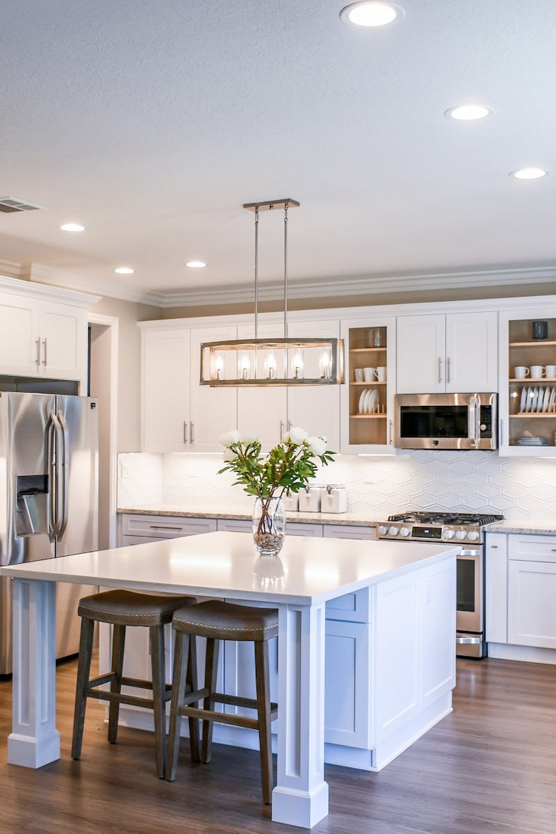 pexels photo 2724748 2724748 Elegant white kitchen featuring an island, modern appliances, and ample natural light.